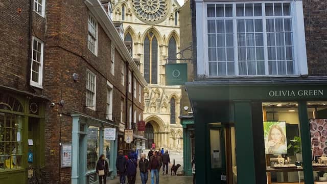Olivia Green jewellers storefront with large windows, people walking, and York Minster in the background.