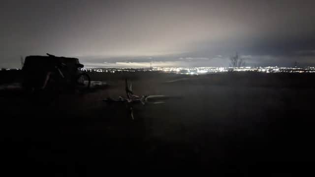 Dimly lit car park at night with a distant view of city lights and a bicycle on the ground.
