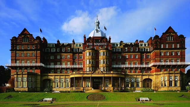 Victorian-style hotel with ornate architecture, large windows, and manicured lawns under a blue sky.