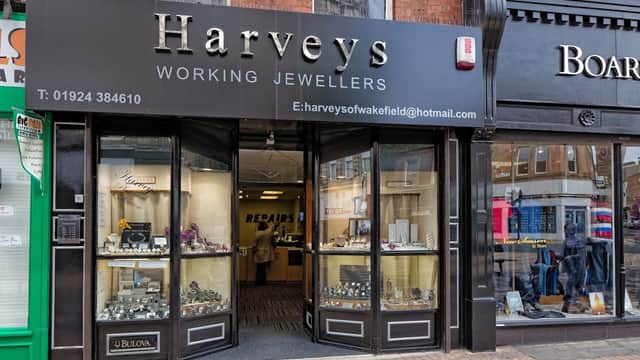 Harvey's Jewellers storefront with glass display cases showcasing jewelry and a sign for repairs.