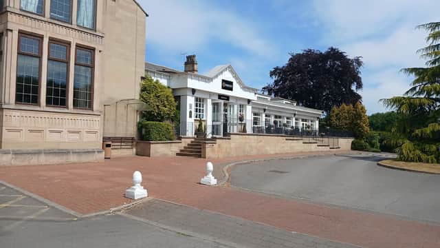 Gomersal Park Hotel features a stone facade, outdoor seating area, and landscaped greenery against a clear blue sky.