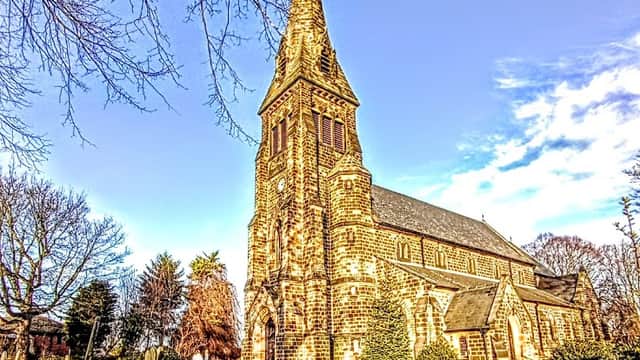 St Paul the Apostle Church with a tall spire, surrounded by trees and a clear blue sky in Monk Bretton, Yorkshire.