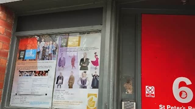 Sign for Leeds Playhouse Costume Hire above a red door, with a display of costumes and event posters in the window.