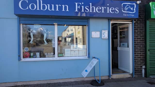 Blue storefront of Colburn Fisheries with a sign for fish and chips, menu displayed, and a welcoming entrance.