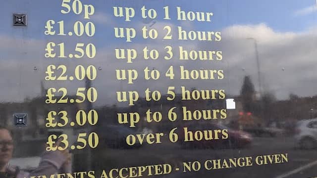 Sign detailing parking charges at Mill Lane Car Park, Brighouse, with hours and fees for various durations.