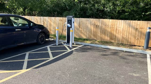 Evolt Network Charging Station with a parked electric car and wooden fence in the background.