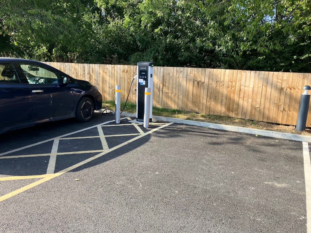 Evolt Network Charging Station with a parked electric car and wooden fence in the background.