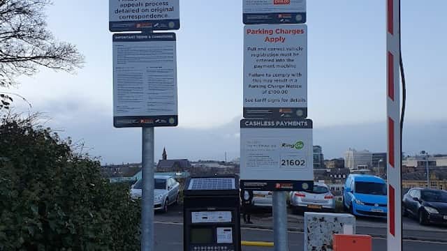 Signposts with parking charges and payment instructions beside a parking meter at Heelis Street Car Park in Barnsley.
