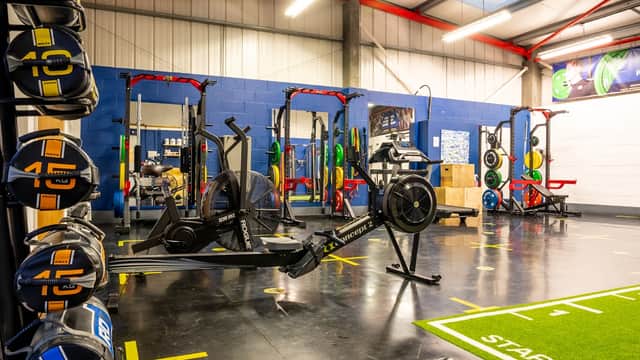 Interior of Lion Fitness gym with weightlifting equipment, rowing machines, and a green turf area marked "START."