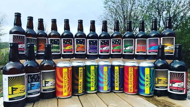 A display of various beer bottles and cans from Yorkshire Dales Brewery, featuring colorful labels and scenic outdoor backdrop.