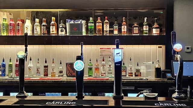 Bar area with illuminated beer taps, shelves of liquor bottles, and a stylish counter in a cozy venue setting.