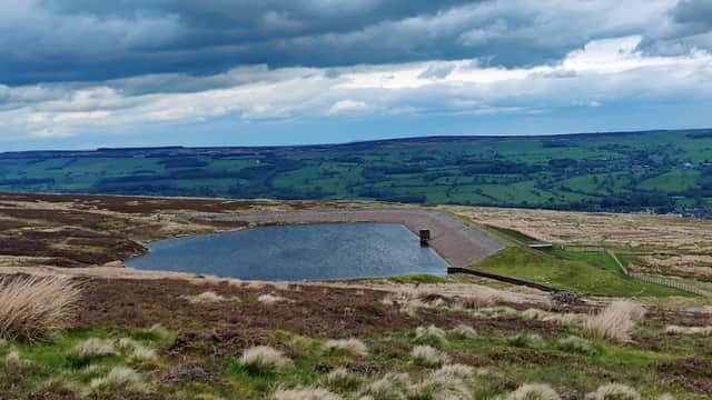 Baildon Moor landscape with a small pond, grassy moorland, and rolling hills under a cloudy sky.