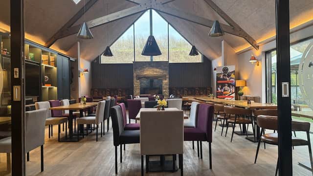 Modern interior of Thimbleby Shooting Ground with wooden beams, a stone fireplace, and various dining tables and chairs.