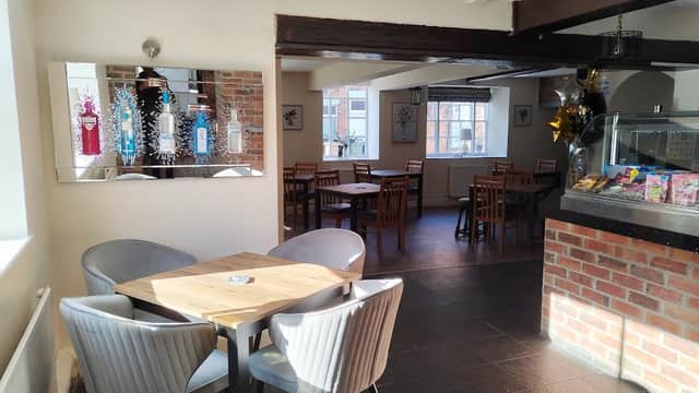 Bright interior of George & Dragon bar featuring wooden tables, chairs, and a mirror reflecting colorful decor.
