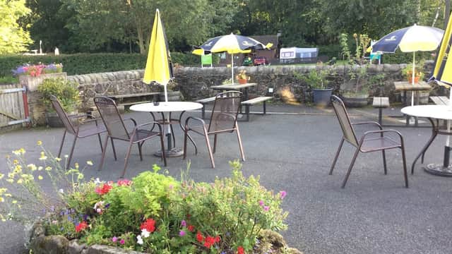 Outdoor seating area with tables and chairs, surrounded by vibrant flowers and umbrellas at The Coach House Inn.