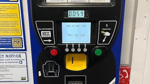 Parking payment machine displaying time, date, and "NOT IN USE" message, with various payment options and instructions.