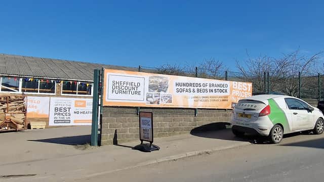 Signage for Sheffield Discount Furniture Store with promotional banners and parked car outside a retail location.