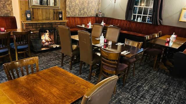 Cozy restaurant interior with wooden tables, leather chairs, a fireplace, and warm lighting in Shipton-by-Beningbrough.