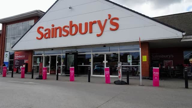 Sainsbury's storefront in Otley, Yorkshire, featuring large orange signage and pink promotional stands outside.