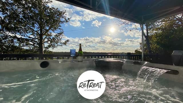 Hot tub with a scenic view of the sky and trees, featuring a bottle of champagne and glasses nearby.