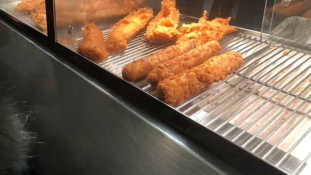 Golden-brown fish fillets and crispy batter in a display case at Oakworth Hall Fisheries.