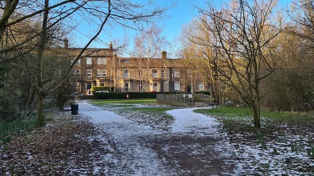 Springfield Park in Guiseley, featuring a path through trees, a grassy area, and historic buildings in the background.