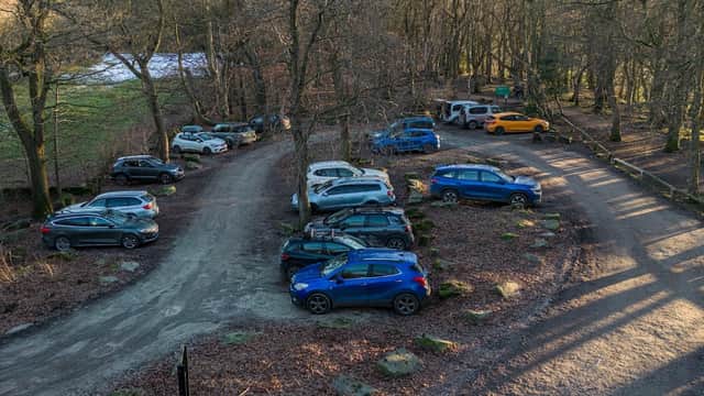 Pay & Display car park surrounded by bare trees, featuring various parked cars on a gravel surface in Grenoside, Yorkshire.