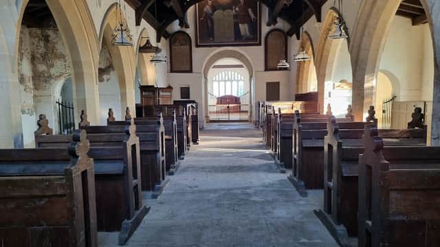Interior of St Martin's Church with wooden pews, arched ceilings, and a large painting at the far end.