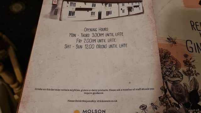 The Red Lion bar menu featuring opening hours and a cozy pub interior with wooden furniture.