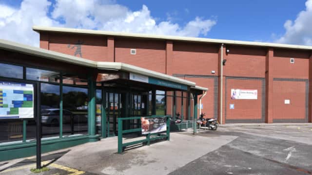Modern brick building with large glass entrance, signage for East Riding Leisure, and blue sky with clouds.