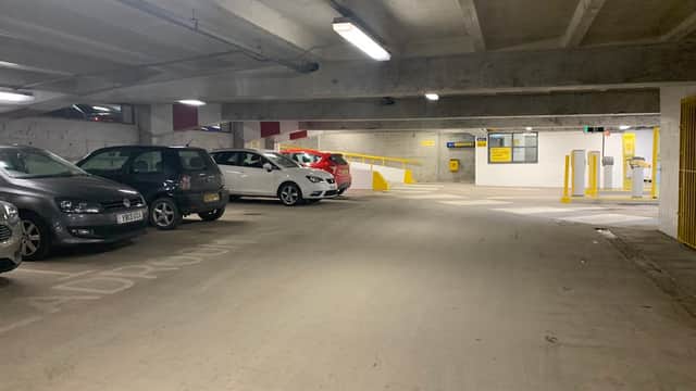 Multi-storey car park interior with parked cars, yellow barriers, and a payment kiosk in Leeds, Yorkshire.