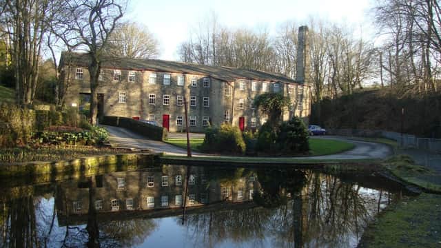 Historic stone cottages and apartments beside a tranquil pond, surrounded by trees in Cullingworth, Yorkshire.