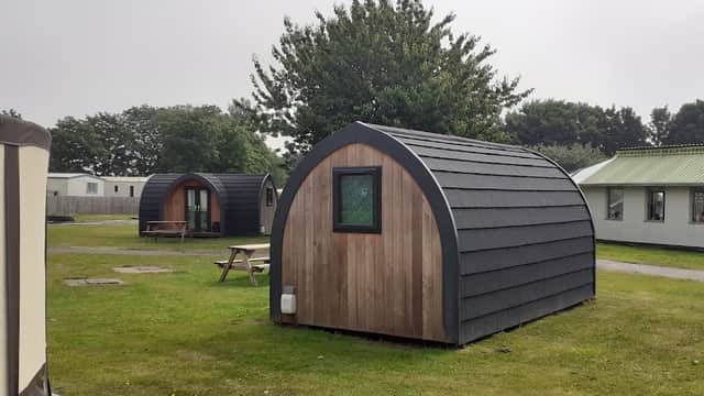 Wooden camping pods in a grassy area, surrounded by trees and other park facilities in Carnaby, Yorkshire.