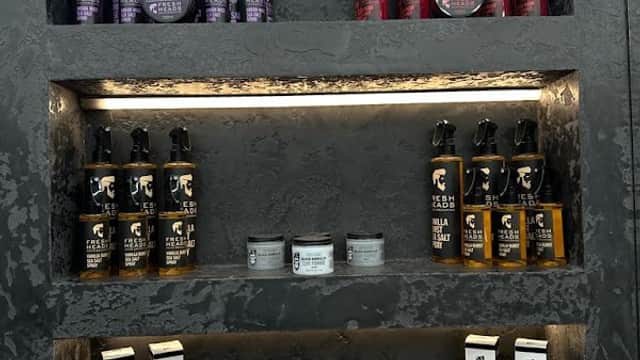 Shelves displaying various grooming products, including sprays, creams, and pomades in stylish packaging.