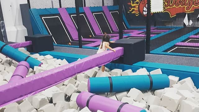 Trampoline park featuring colorful trampolines, foam blocks, and a child navigating a play area.