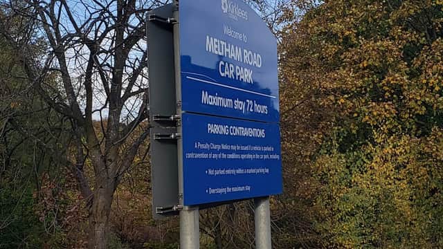 Sign for Meltham Road Car Park with parking regulations and maximum stay details, surrounded by trees in autumn colors.