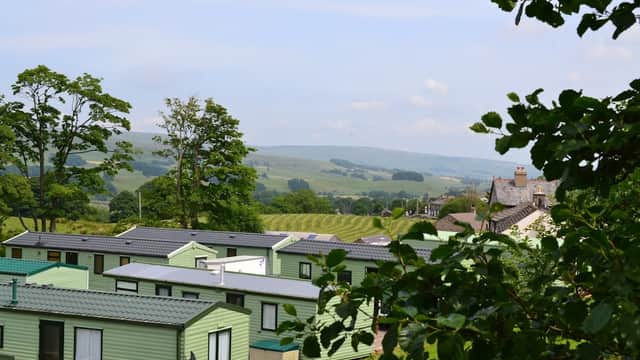 Green caravans nestled in a scenic landscape with rolling hills and trees in Burtersett, Yorkshire.