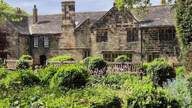 Historic stone building surrounded by lush gardens and greenery at Oakwell Hall Country Park.