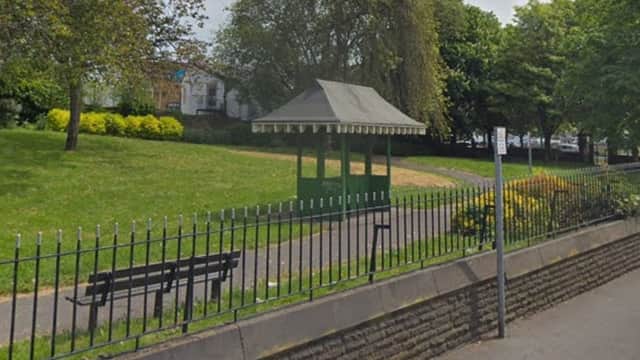 Green gazebo surrounded by trees and shrubs, with a path and benches in Sparrow Park, Barnsley.