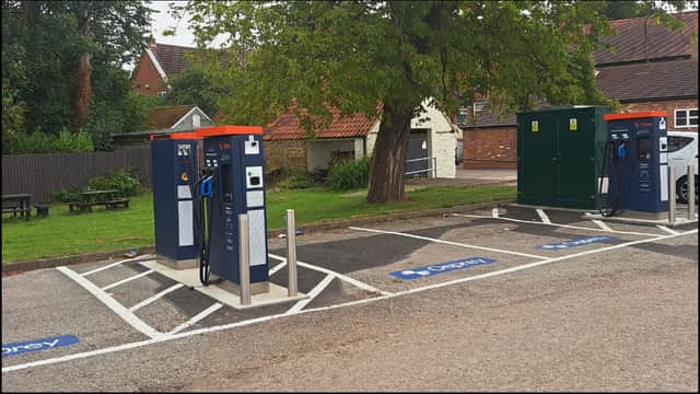 Osprey Charging Station with multiple EV chargers and a green utility box in a parking area, surrounded by trees.