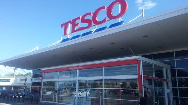 Tesco Superstore exterior with large red signage, glass entrance, and shoppers outside in Catterick Garrison, Yorkshire.