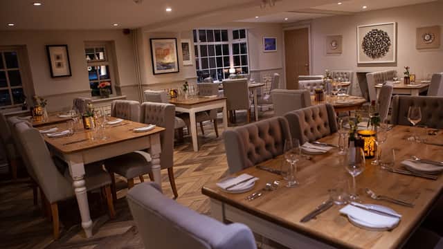 Cozy dining area with wooden tables, upholstered chairs, and soft lighting, creating a warm atmosphere.
