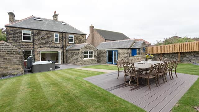 Stone building with a manicured lawn, outdoor dining set, hot tub, and patio area in Millhouse Green, Yorkshire.