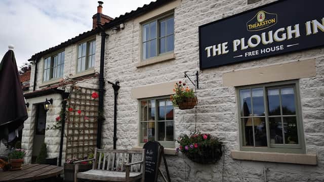 Charming pub exterior with stone walls, hanging flower baskets, and outdoor seating in Wombleton, Yorkshire.