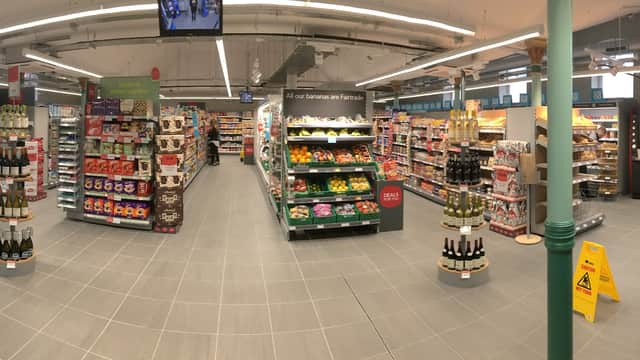 Brightly lit corner shop interior with aisles of groceries, drinks, and snacks, featuring signage and a clean layout.