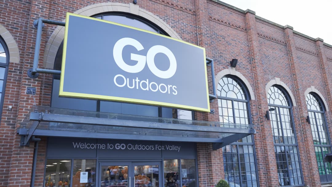 Large "GO Outdoors" sign on a brick building with arched windows, welcoming customers to the sports shop.