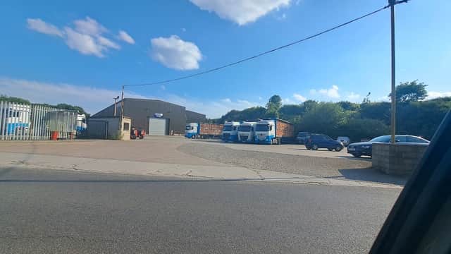 Cullingworth Commercials Ltd yard with trucks, cars, and a large industrial building under a blue sky.
