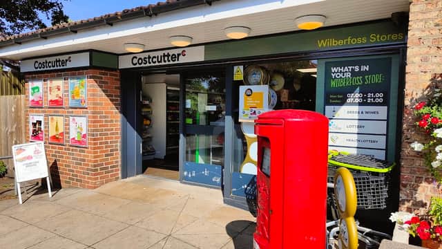 Costcutter store entrance with signage, lottery display, and a red post box outside in Wilberfoss, Yorkshire.