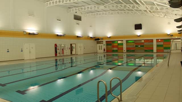 Indoor swimming pool with clear water, tiled walls, and colorful panels in the background. Brightly lit environment.