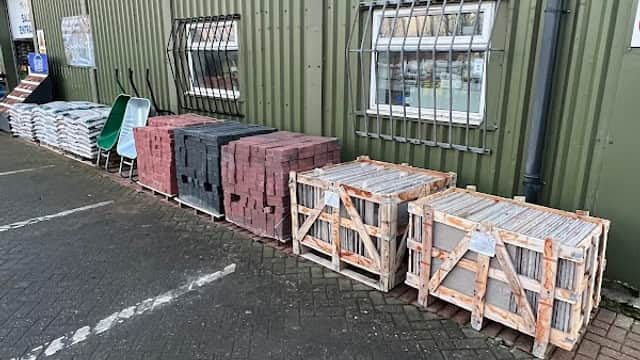 Bricks and building materials stacked outside a green metal building with "Yorkshire Independent Building Supplies Ltd" sign.